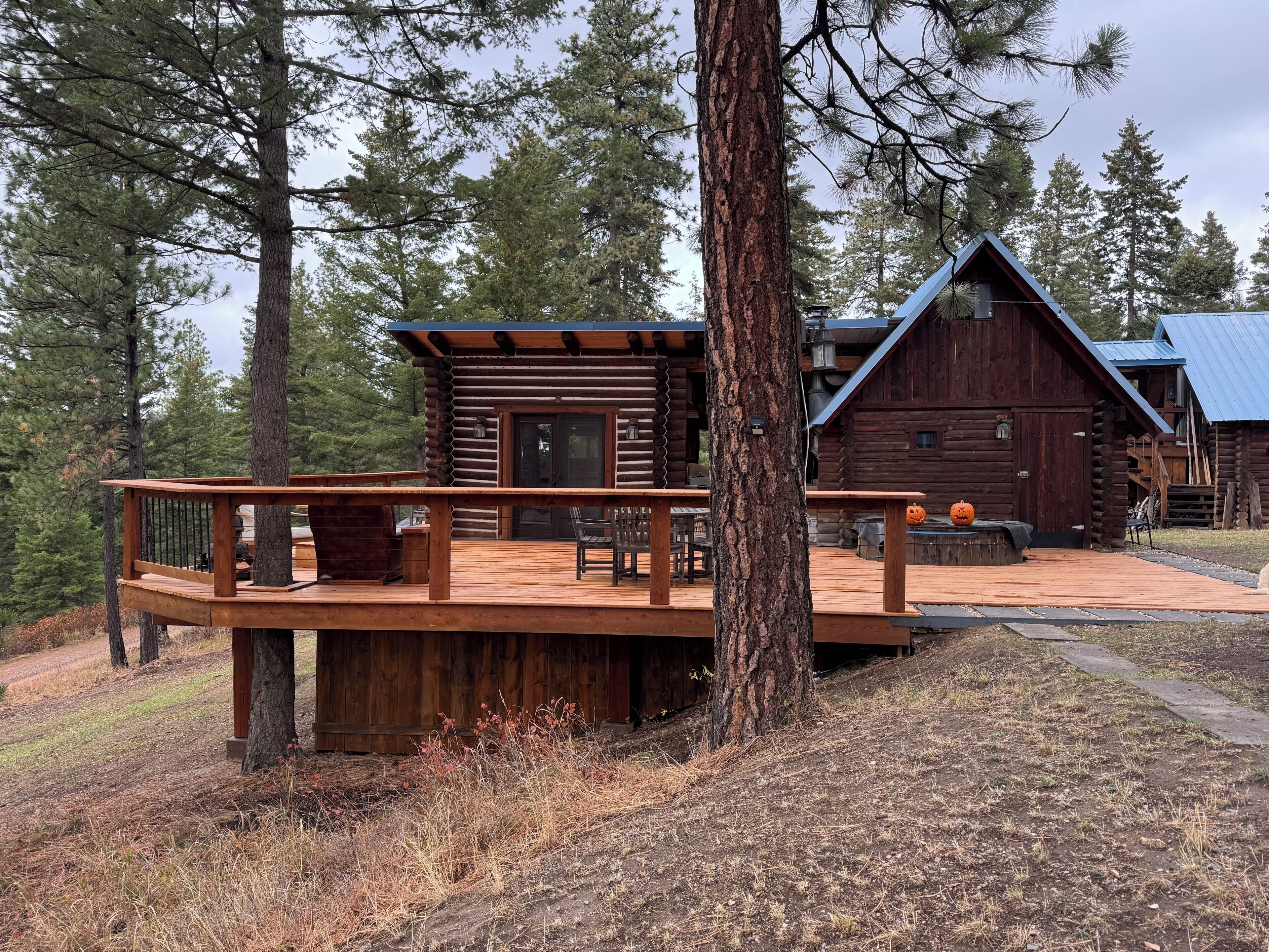 A log cabin with a wooden deck and outdoor seating area.