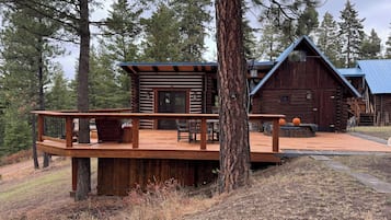 A log cabin with a wooden deck and outdoor seating area.