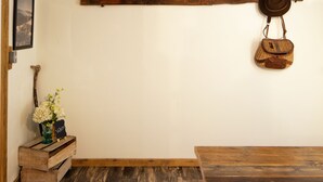 Una habitación rústica con una mesa de comedor de madera, un banco, un perchero de madera y un pequeño cofre de madera.