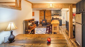 Una cocina acogedora con estufa de leña, electrodomésticos modernos y comedor con mesa y sillas.