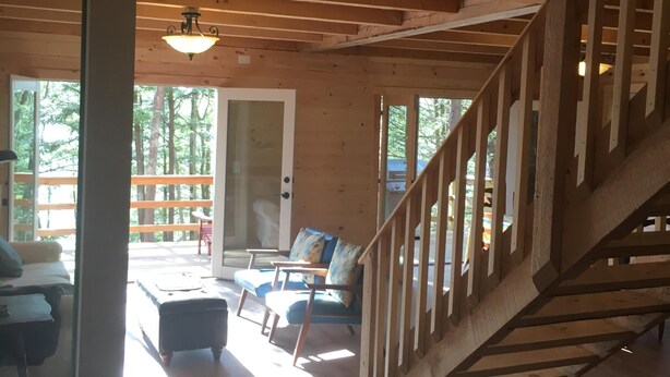 Un interior de madera con una escalera, un sofá y una zona de comedor.
