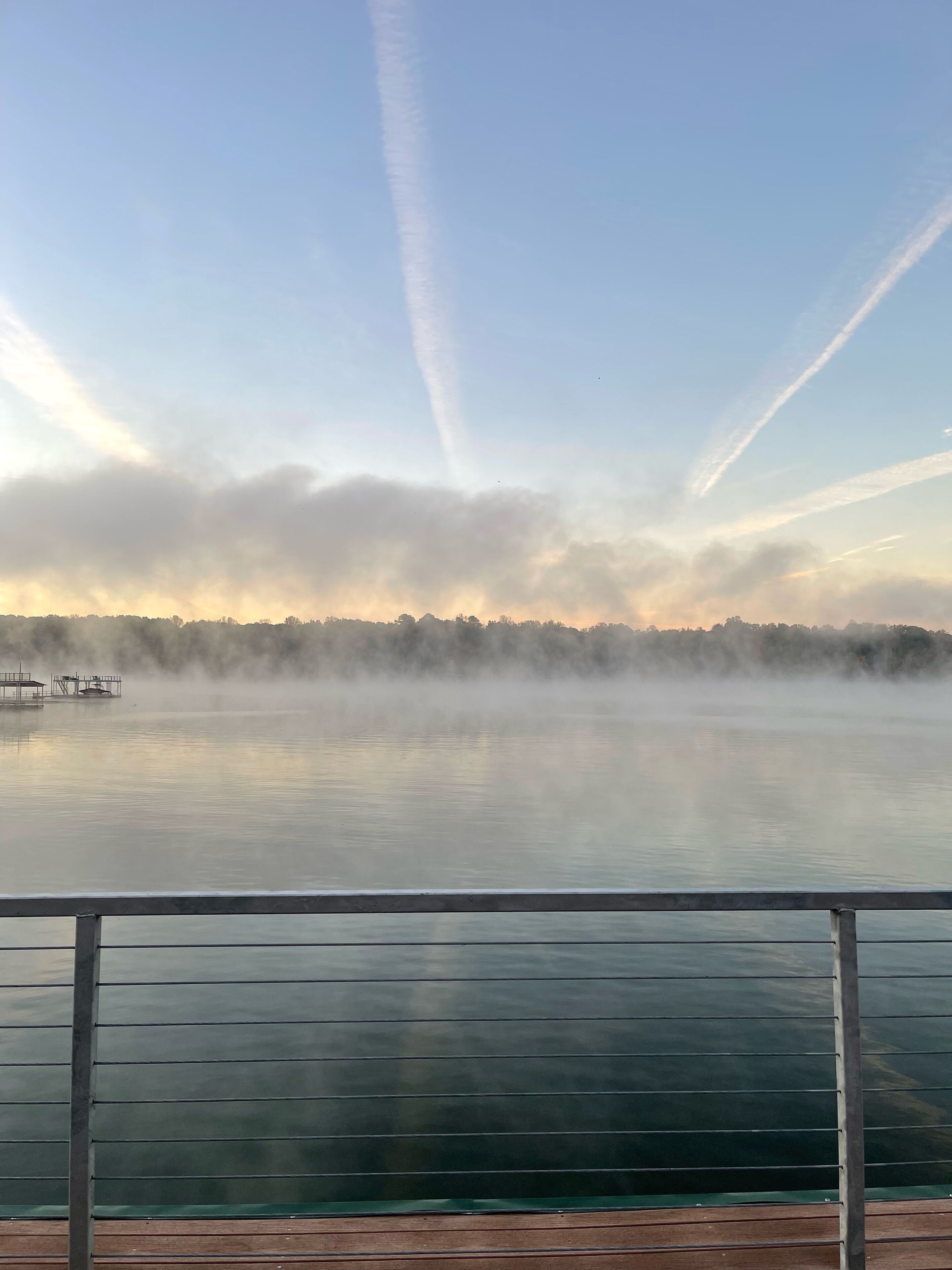 En rolig sø med en træbrygge og gelænder i forgrunden.