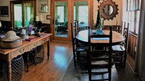 Uma sala de jantar com uma mesa de madeira, cadeiras, um candelabro e um pinheiro de Natal.