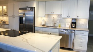 Una cocina moderna con armarios blancos, electrodomésticos de acero inoxidable y encimera de mármol.