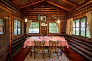 Cozy cabin-style room with a dining area, featuring a wooden interior, high ceiling, and exposed beams.