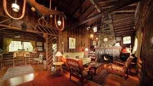 A log cabin interior with a fireplace, wooden furniture, and a cozy ambiance.