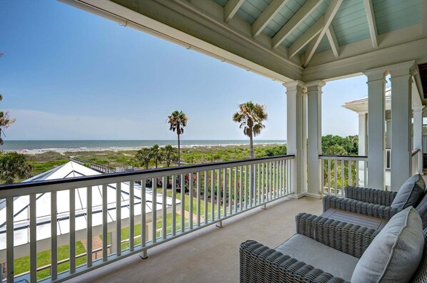A covered balcony with a view of the beach and ocean.