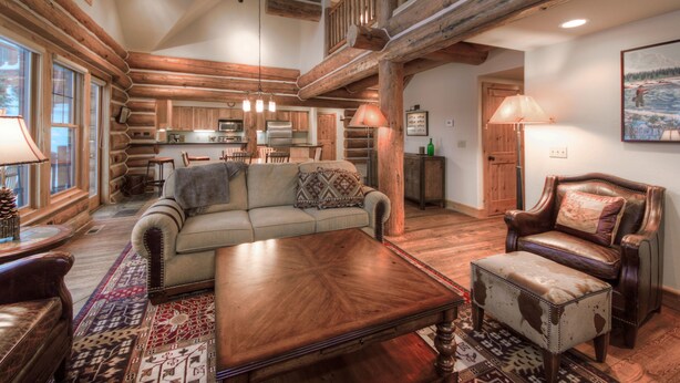 Un intérieur spacieux de chalet en bois, comprenant un grand salon, une cuisine et un coin repas.