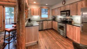 Une cuisine moderne avec des meubles en bois, des appareils électroménagers en acier inoxydable et un grand îlot central.