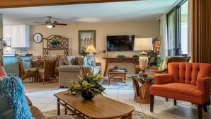 A living room with a sofa, armchair, coffee table, and a dining area with chairs and a table. - OCEAN VIEW - SLEEP 6! -Single Level - Family Room -No Stairs-Steps to Beach! (Kihei)