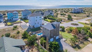 Una zona residencial costera con varias casas, una piscina y vistas al océano.