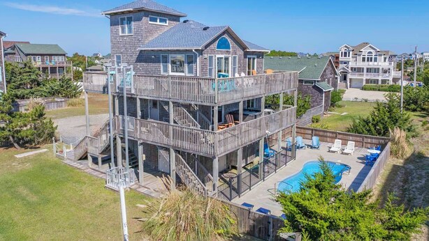 Una casa de varios pisos con una terraza amplia y una piscina.