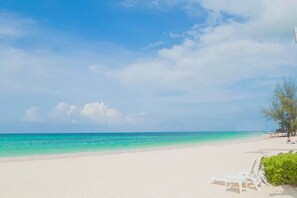 A beach with a clear sky, calm sea, and a few people in the distance. - Beachfront Playa Turquesa 2 BR/2 BA Penthouse Condo W/Rooftop 50mbps WIFI (Punta Cana)