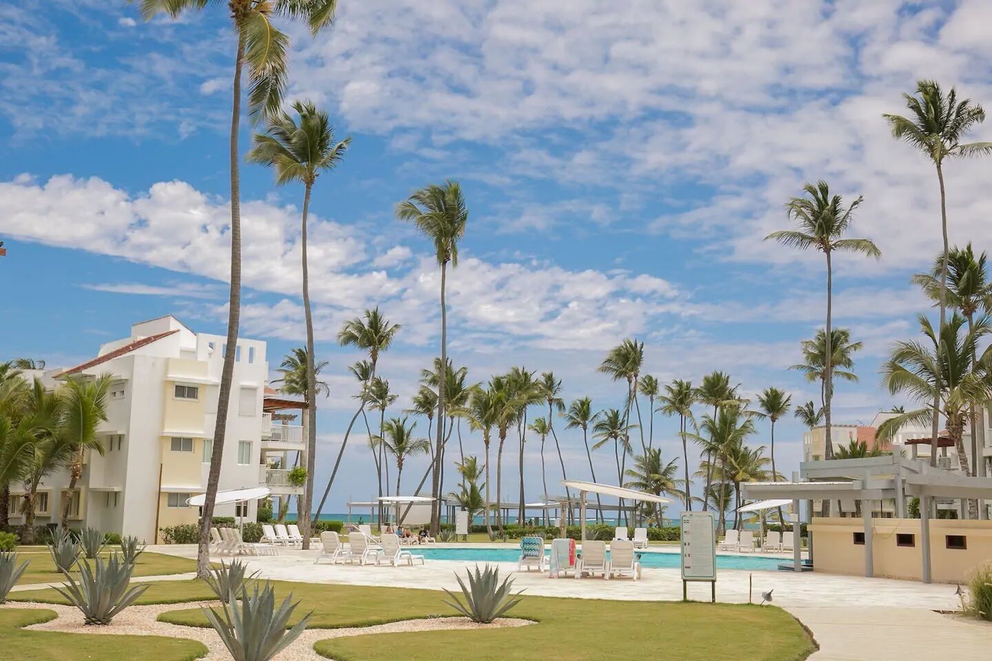 Ein Resort mit Swimmingpool, Palmen und blauem Himmel.