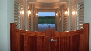A corridor with a wooden bench, flanked by walls with vertical slats and wall-mounted lights. - Beautiful Oceanfront 5 Bedroom Home With Pool  (Isle of Palms)
