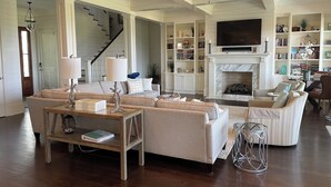 A spacious living room with a fireplace, a television, and a bookshelf. - Beautiful Oceanfront 5 Bedroom Home With Pool  (Isle of Palms)