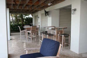 Een overdekt terras met houten meubels, waaronder stoelen en een tafel.