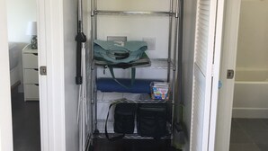 A compact storage unit with shelves, a hanging bag, and a container. - North Shore Ocean-View Garden Cottage near Paia – Maui by the Sea (Paia)