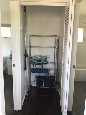 A compact storage unit with shelves, a hanging bag, and a container.