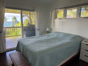 Een slaapkamer met een bed, nachtkastje, een bankje en uitzicht op het omliggende landschap.