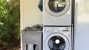 A laundry area with stacked washing machines and a refrigerator. - North Shore Ocean-View Garden Cottage near Paia – Maui by the Sea (Paia)