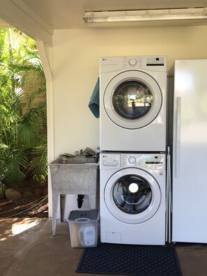 A laundry area with stacked washing machines and a refrigerator.