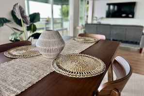 Una mesa de comedor con individuales tejidos y un florero.
