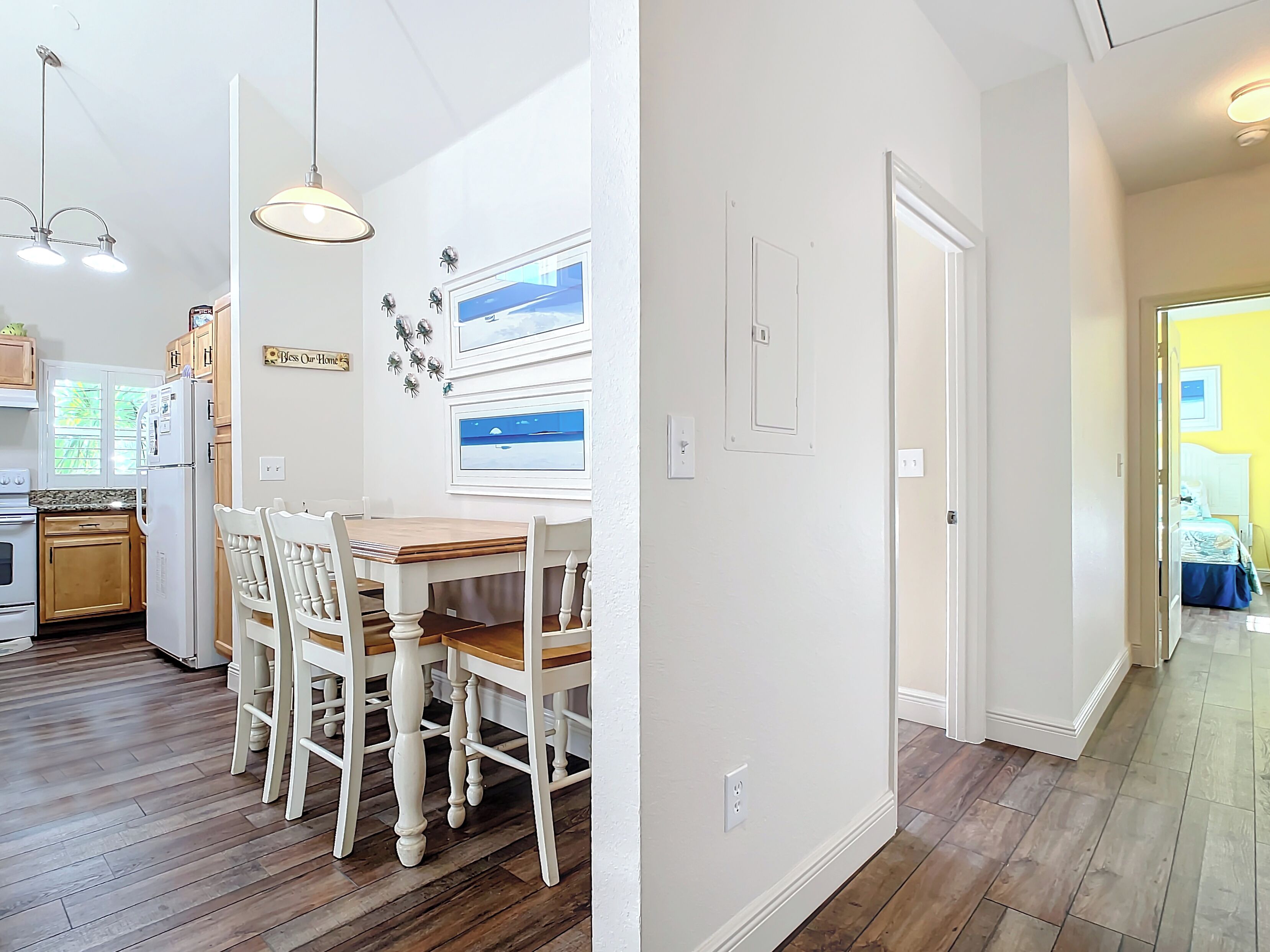 A modern kitchen with wooden cabinets, a dining table with chairs, and a refrigerator.