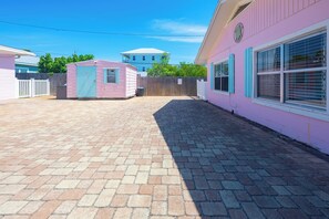 A pink building with a small attached structure, a fenced yard, and a paved walkway.