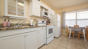 A kitchen with white cabinets, a microwave, a stove, and a refrigerator.