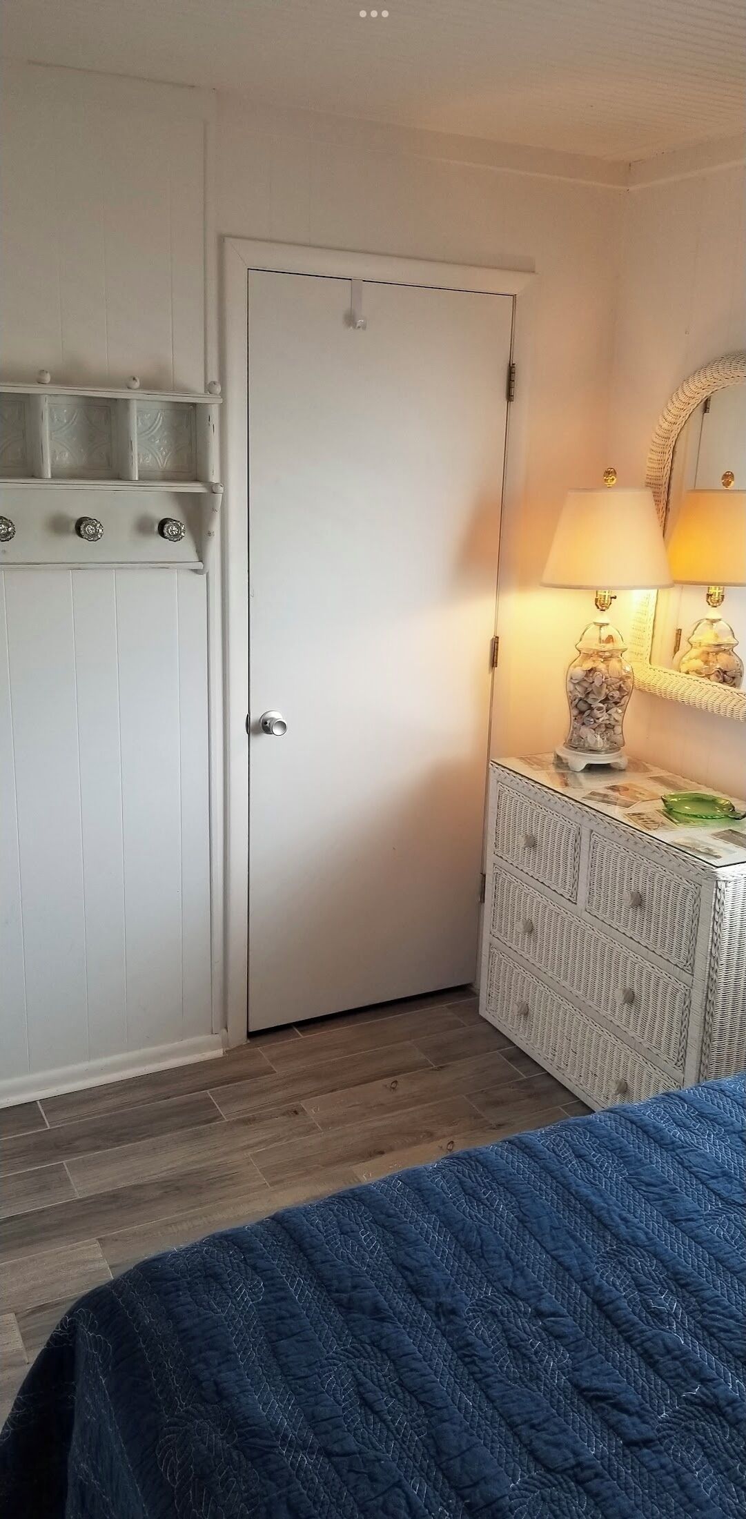 A bedroom with a bed, a dresser, a door, and a lamp.