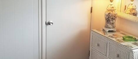A bedroom with a bed, a dresser, a door, and a lamp.