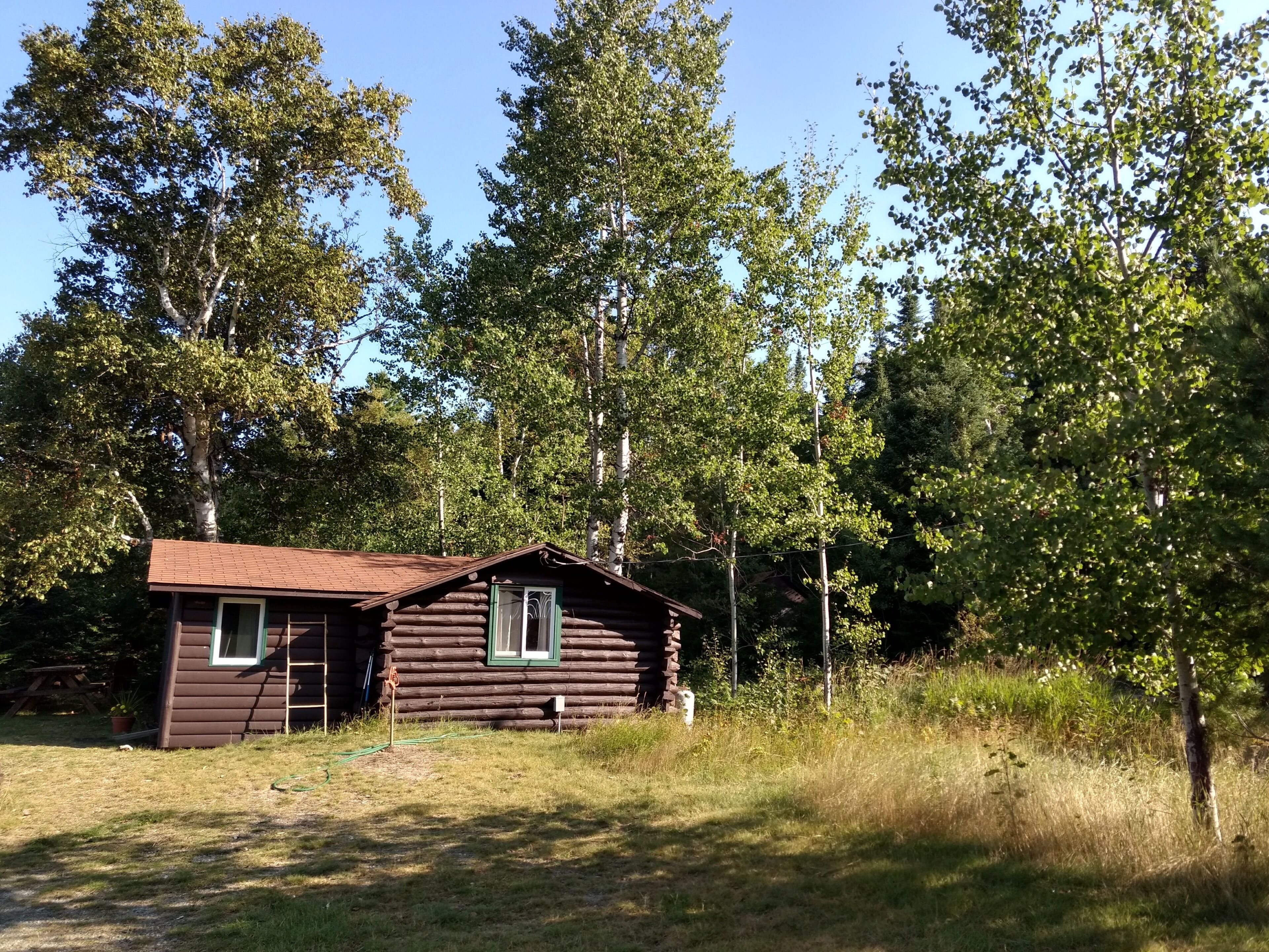 Une cabane rustique à l’extérieur brun, avec une petite fenêtre et une porte.