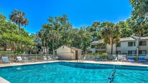 A swimming pool with clear blue water, surrounded by lounge chairs and palm trees.
