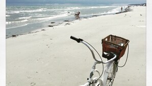 A bicycle with a basket on a sandy beach.