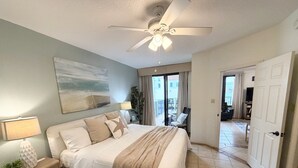 A bedroom with a bed, nightstand, lamp, and a painting on the wall. - Direct Gulf Front View And Your Very Own Private Pier 504W (Orange Beach)