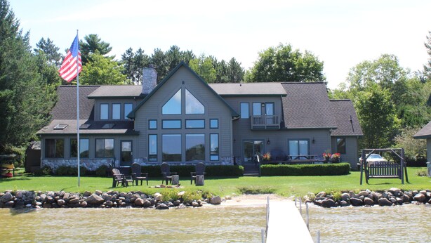 A large two-story building with a prominent American flag, a stone chimney, and a well-maintained lawn with outdoor seating.