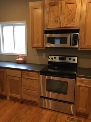 A kitchen with wooden cabinets, a stainless steel stove, and a microwave.