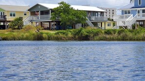 Une propriété située au bord de l’eau, comprenant plusieurs bâtiments, notamment une maison avec un balcon et une plus grande construction dotée d’un porche.