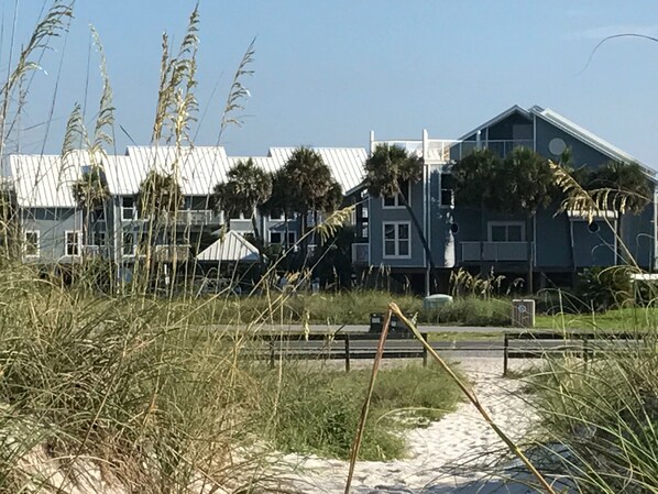 A beachfront property with a large building featuring multiple windows and a sloped roof.