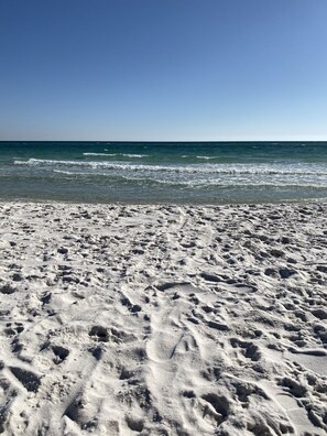 A sandy beach with footprints leading to the water.