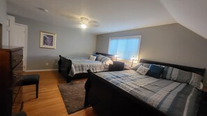A bedroom with two beds, a dresser, a chair, a window with blinds, and a ceiling light.