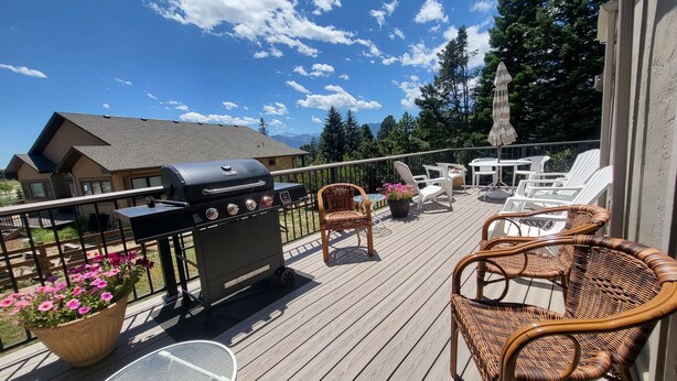 A deck with a grill, wicker chairs, and a table. - Spacious Home in Quiet Area - Minutes to Attractions, Music, Restaurants & USAFA (Colorado Springs)