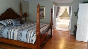 A bedroom with a four-poster bed, a wooden floor, a door, and a view to a balcony. - Spacious Home in Quiet Area - Minutes to Attractions, Music, Restaurants & USAFA (Colorado Springs)