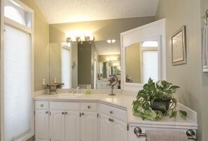 A bathroom with a white vanity, a large mirror, and a potted plant.