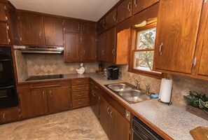 Una cocina con armarios de madera, electrodomésticos de acero inoxidable y un ventanal.