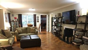Una sala de estar con un conjunto de sofá, una mesa de centro, una chimenea y un televisor montado en la pared.