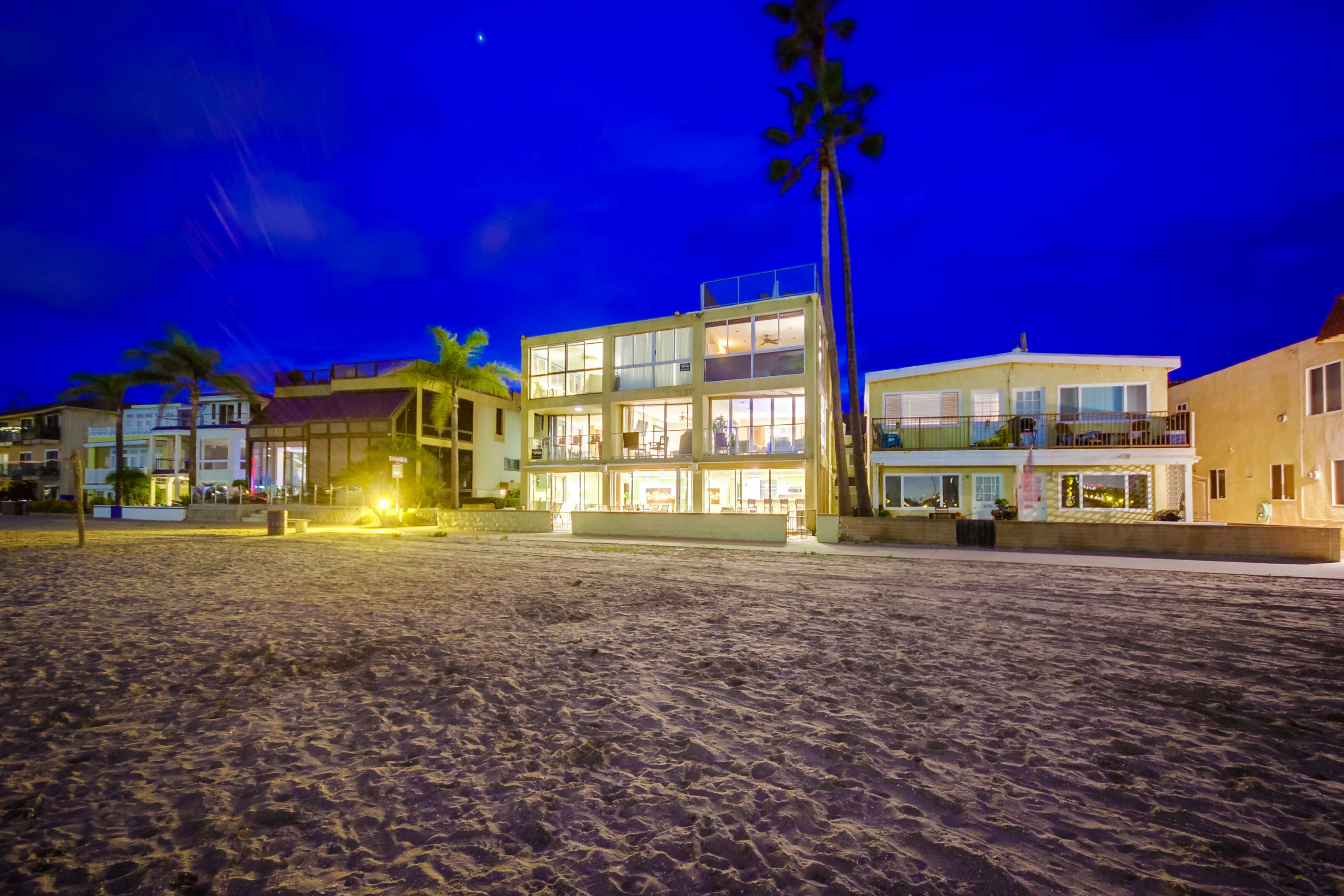 A beachfront property with a two-story building, a balcony, and a sandy beach.