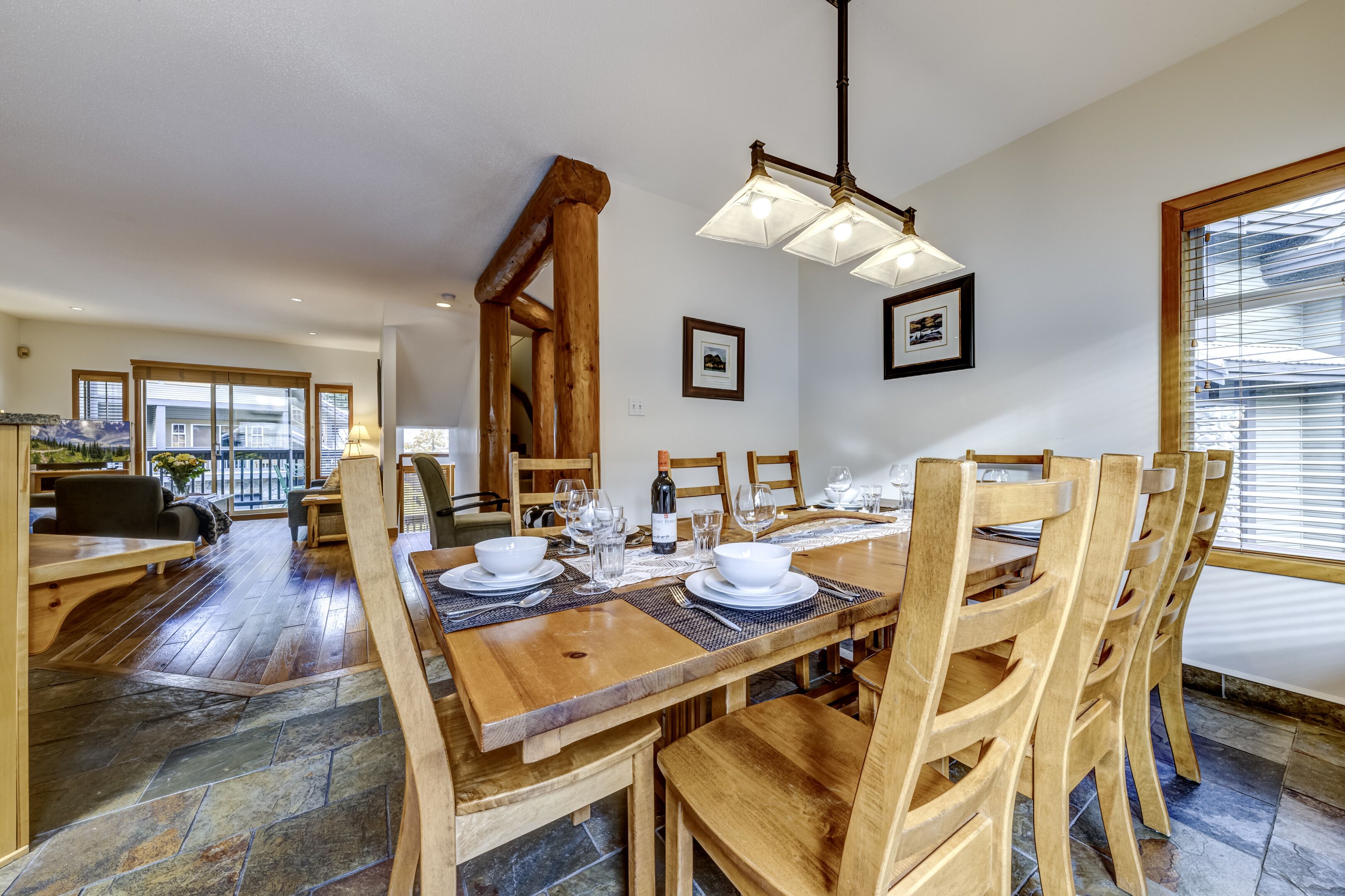 Un comedor con una mesa de madera dispuesta para cuatro personas, rodeada de sillas de madera.