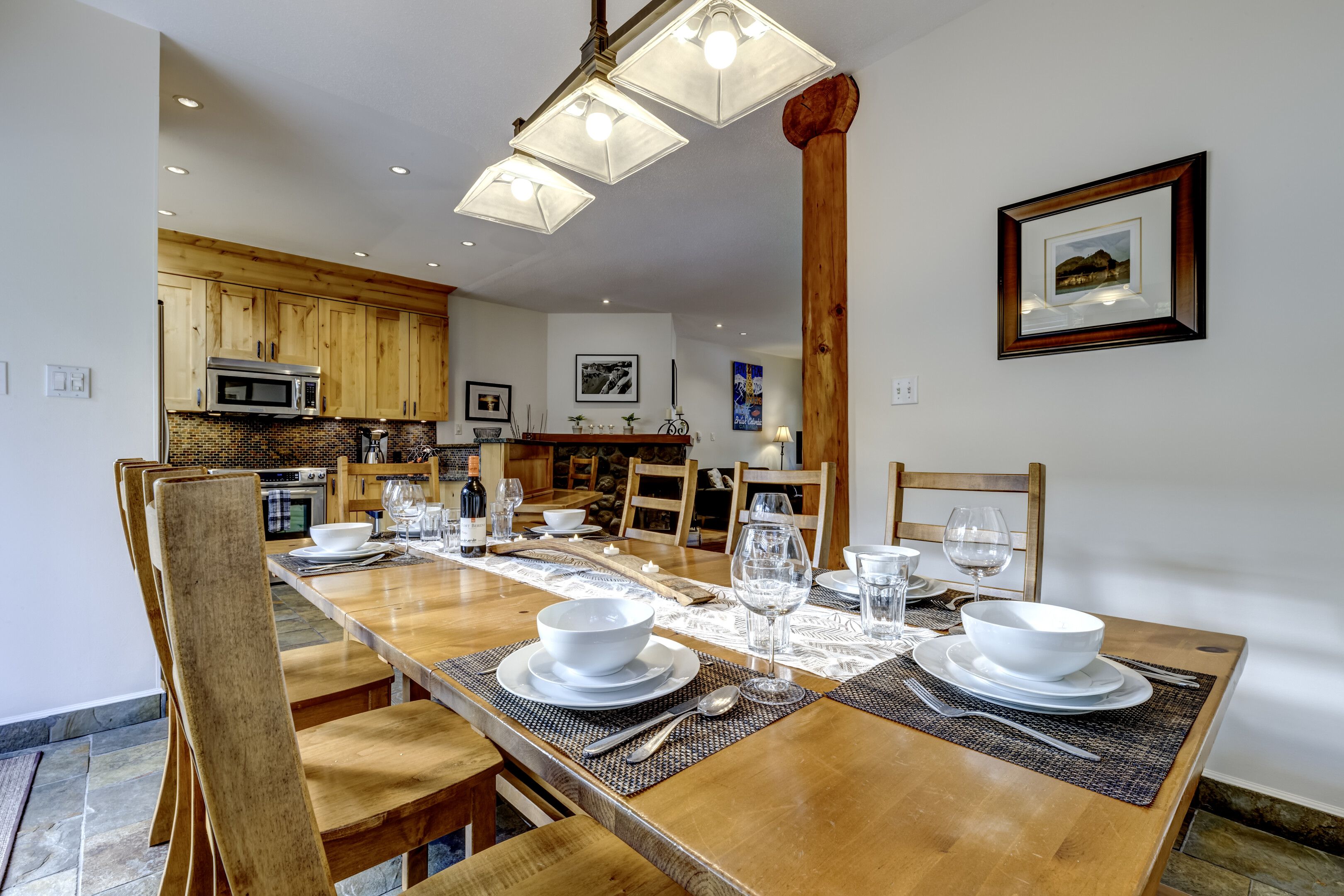 Un comedor con una larga mesa de madera dispuesta para una comida, rodeado de sillas de madera.